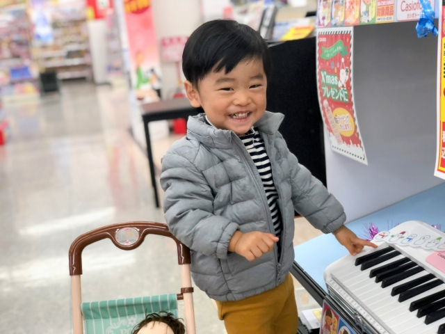 おもちゃのピアノを笑顔で触る男の子の様子
